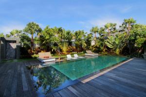 uma piscina com espreguiçadeiras e palmeiras em Villa Amba Laba by Optimum Bali Villas em Seminyak