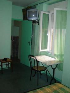 a room with a table and a tv and a window at Hotel Restaurant du Lion d'Or in Château-Chinon