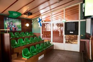 uma sala de espera com cadeiras verdes e uma televisão em Hotel Adlon em Mariehamn