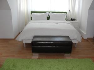 a bedroom with a bed with a black leather ottoman at The Square Coburg in Coburg