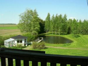 a view of a house with a pond in a field at Majatalo Myötätuuli in Pitkäjärvi