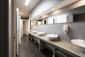 Baño con 4 lavabos y una fila de espejos en Winstrup Hostel, en Lund