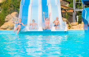 een groep mensen die van een glijbaan in een zwembad springen bij Camping RCN Le Moulin de la Pique in Belvès