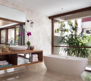 a bathroom with a large tub and a plant at Amnaya Resort Kuta in Kuta