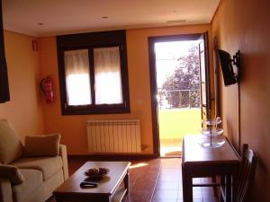 sala de estar con sofá, mesa y ventana en Apartamentos Casa Bernabé, en Miengo