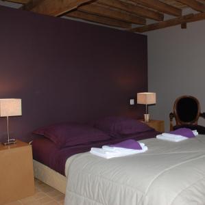 a bedroom with a large bed with purple pillows at Chateau de Vaux in Gesnes-le-Gandelin