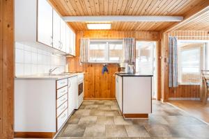 a kitchen with white appliances and wooden walls at Haulundsvej 120 in Sæby