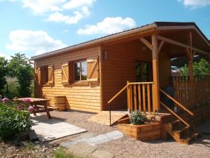 a small wooden cabin with a porch and a table at Chalet la Noisetiere Armalou in Pouilly-sur-Loire