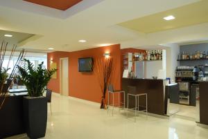 eine Küche mit orangefarbenen Wänden und eine Bar mit Hockern in der Unterkunft San Giorgio Hotel in San Giórgio di Nogaro