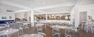 un restaurante con mesas y sillas blancas y una cocina en Gava Waterman Milna Resort – All Inclusive, en Milna