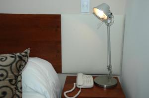 a bed with a lamp and a phone on a table at Palm Beach Plaza Hotel in Montevideo