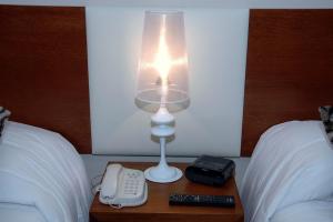 a lamp on a nightstand with a phone and a remote control at Palm Beach Plaza Hotel in Montevideo