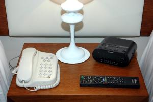 a table with a telephone and a lamp and a remote control at Palm Beach Plaza Hotel in Montevideo
