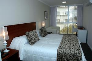 a bedroom with a large white bed with pillows at Palm Beach Plaza Hotel in Montevideo