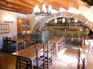 un restaurante con mesas de madera y una pared de piedra en Hostal Els Roures, en Camprodon