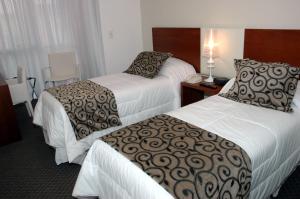a hotel room with two beds and a lamp at Palm Beach Plaza Hotel in Montevideo