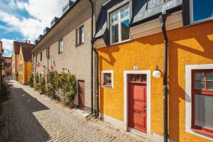 a cobblestone street with yellow buildings and a red door at Hotell Gute in Visby