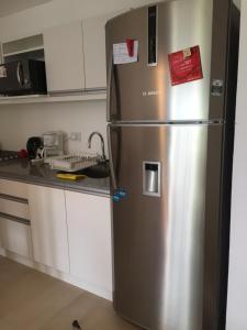 a stainless steel refrigerator in a kitchen with white cabinets at Departamento en Tigre con Pileta y cochera in Tigre