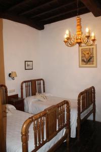 1 dormitorio con 2 camas y lámpara de araña en Casona de Treviño en Cosgaya