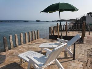 twee stoelen en een paraplu naast het water bij Villa Pula Mare in Pula