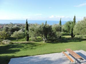 un parque con un banco, árboles y el océano en Villa Theodora, en Lakíthra