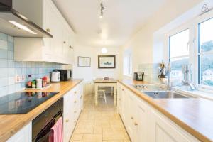 a large kitchen with white cabinets and a sink at Fisherman's Cottage in Saint Mawes