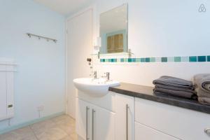 a white bathroom with a sink and a mirror at Fisherman's Cottage in Saint Mawes