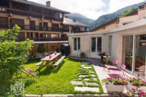 un cortile con tavolo da picnic, sedie e un edificio di La Maison Rapin a Valloire