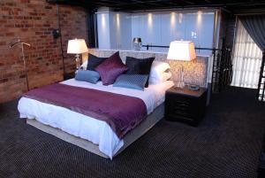 1 dormitorio con 1 cama grande y 2 lámparas en Manhattan Apartments, en Ciudad del Cabo
