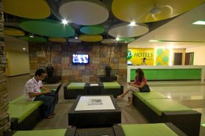 two people sitting on couches in a hotel lobby at Go Hotels Dumaguete in Dumaguete