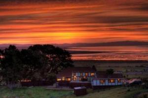 a house on a hill with a sunset in the background at Chartré Manor B&B in Thames