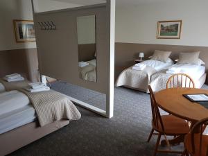 una camera d'albergo con due letti, un tavolo e uno specchio di Lamb Inn Öngulsstadir ad Akureyri