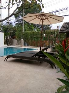 a lounge chair with an umbrella next to a swimming pool at Yi's Garden Villa in Chiang Mai