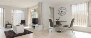 a living room with a table and chairs and a clock at Citystay - Vesta Apartments in Cambridge