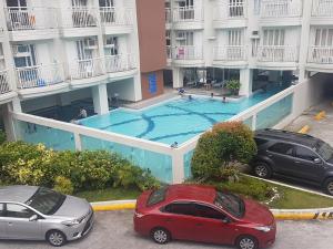 two cars parked in front of a building with a swimming pool at EAM LAKE VIEW @ TAGAYTAY PRIME RESIDENCES in Tagaytay