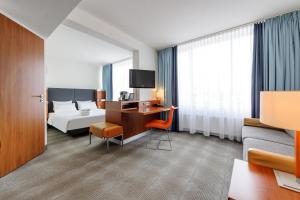 a hotel room with a bed and a desk with a tv at Novotel Erlangen in Erlangen