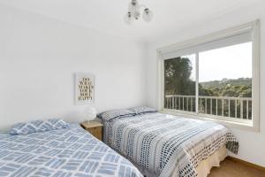 a bedroom with two beds and a large window at Tyrone Beach House in Rye