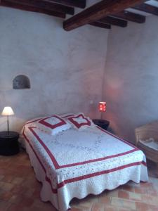 a bedroom with a bed with a red and white blanket at La Maison derrière la Fontaine in Buis-les-Baronnies