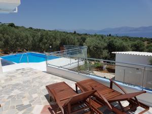 a balcony with two chairs and a swimming pool at Villa Konaki in Grammatiko