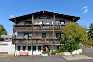 a building with a balcony with a bench in front of it at Antjes Schmankerlhotel und Restaurant in Tröstau