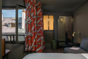 a room with a bed and a window with a view at Hôtel Louvre Piemont in Paris