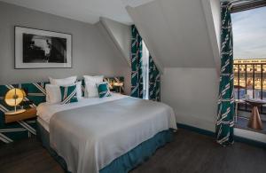 - une chambre avec un grand lit blanc et une fenêtre dans l'établissement Hôtel Louvre Piemont, à Paris