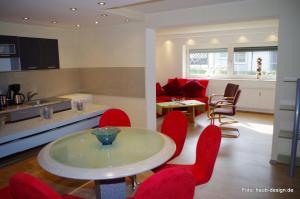 a kitchen and living room with a table and red chairs at Taunus Im Grünen in Espa