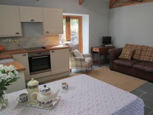 a kitchen and living room with a table and a couch at Danygraig Cottage in Carmarthen