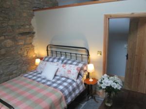 a bedroom with a bed and a stone wall at Danygraig Cottage in Carmarthen