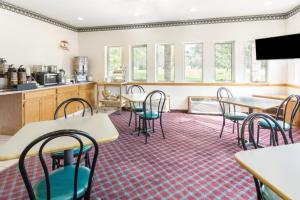 a room with tables and chairs and a kitchen at Super 8 by Wyndham Cresco IA in Cresco