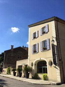 a white building with potted plants in front of it at L'Instant Sévigné in Grignan