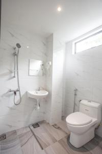 a white bathroom with a toilet and a sink at The Marion Hotel in Johor Bahru