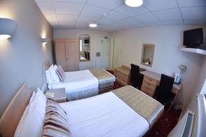 a hotel room with two beds and a desk at The Mayfair Hotel - OCEANA COLLECTION in Bournemouth