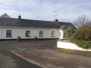 a white house with a driveway in front of it at Teasy's cottage in Armagh